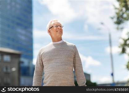 leisure and people concept - senior man walking along summer city street. senior man walking along summer city street