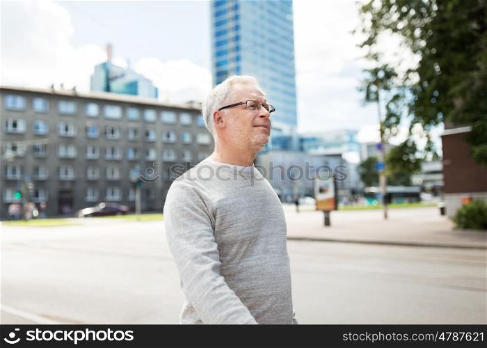 leisure and people concept - senior man walking along summer city street. senior man walking along summer city street