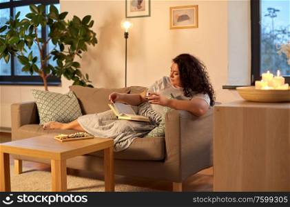 leisure and people concept - woman reading book and drinking red wine at home in evening. woman reading book and drinking red wine at home
