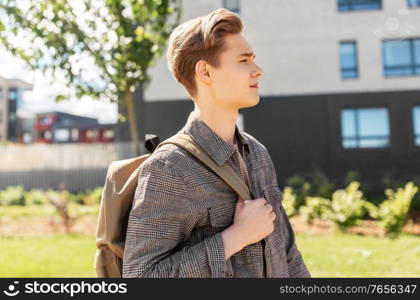 leisure and people concept - young man or teenage student boy with backpack walking in city. teenage student boy with backpack in city