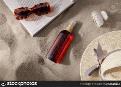 leisure and summer holidays concept - open magazine, sunscreen, hair clip and sunglasses on beach sand. magazine, sunglasses and sunscreen on beach sand