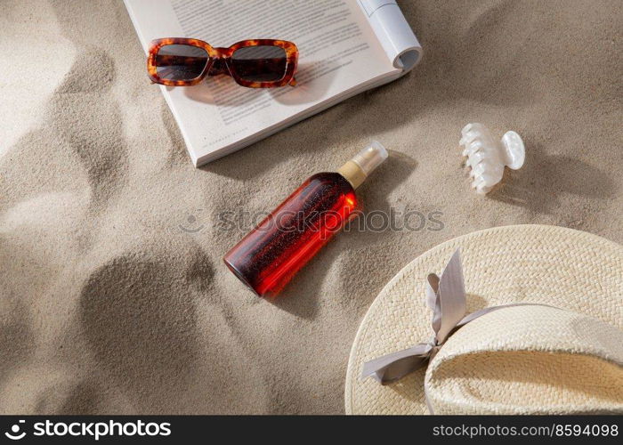 leisure and summer holidays concept - open magazine, sunscreen, hair clip and sunglasses on beach sand. magazine, sunglasses and sunscreen on beach sand