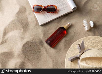 leisure and summer holidays concept - open magazine, sunscreen, hair clip and sunglasses on beach sand. magazine, sunglasses and sunscreen on beach sand