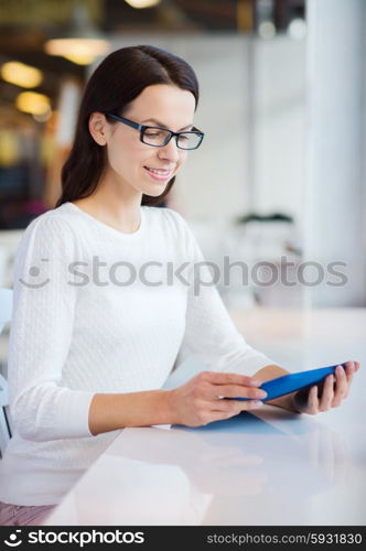 leisure, business, people, technology and lifestyle concept - smiling young woman in eyeglasses with tablet pc computer at cafe