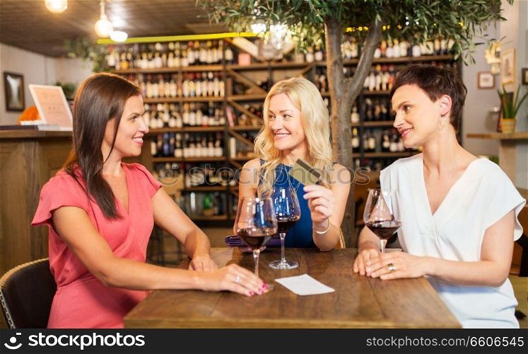 leisure, cashless payment and lifestyle concept - happy women with credit card paying bill at restaurant or wine bar. women with credit card at wine bar or restaurant