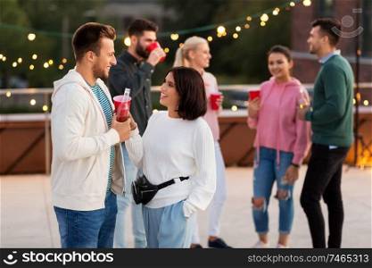 leisure, celebration and people concept - happy friends clinking drinks in party cups toasting at rooftop. friends with drinks in party cups at rooftop