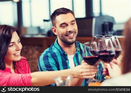 leisure, celebration, drinks, people and holidays concept - happy couple and friends clinking glasses of wine at restaurant. friends clinking glasses of wine at restaurant