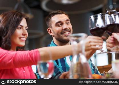 leisure, celebration, drinks, people and holidays concept - happy couple and friends clinking glasses of wine at restaurant