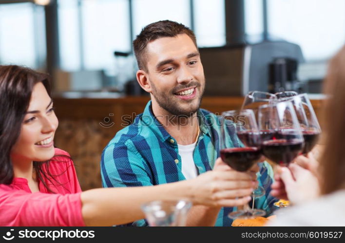 leisure, celebration, drinks, people and holidays concept - happy couple and friends clinking glasses of wine at restaurant