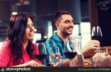 leisure, celebration, food and drinks, people and holidays concept - happy couple and friends clinking glasses of wine at restaurant. friends clinking glasses of wine at restaurant