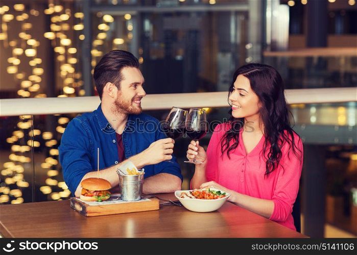leisure, celebration, food and drinks, people and holidays concept - smiling couple having dinner and drinking red wine at date in restaurant. happy couple dining and drink wine at restaurant