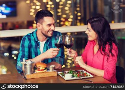 leisure, celebration, food and drinks, people and holidays concept - smiling couple having dinner and drinking red wine at date in restaurant. happy couple dining and drink wine at restaurant