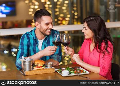 leisure, celebration, food and drinks, people and holidays concept - smiling couple having dinner and drinking red wine at date in restaurant