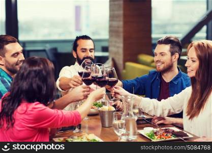 leisure, celebration, food and drinks, people and holidays concept - smiling friends having dinner and drinking red wine at restaurant. friends dining and drinking wine at restaurant. friends dining and drinking wine at restaurant