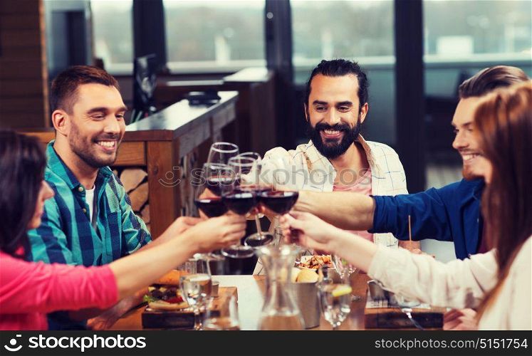 leisure, celebration, food and drinks, people and holidays concept - smiling friends having dinner and drinking red wine at restaurant. friends dining and drinking wine at restaurant