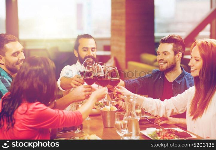 leisure, celebration, food and drinks, people and holidays concept - smiling friends having dinner and drinking red wine at restaurant. friends dining and drinking wine at restaurant