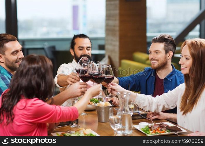 leisure, celebration, food and drinks, people and holidays concept - smiling friends having dinner and drinking red wine at restaurant