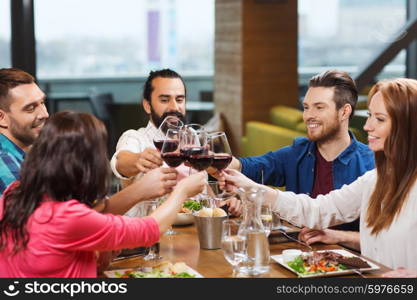 leisure, celebration, food and drinks, people and holidays concept - smiling friends having dinner and drinking red wine at restaurant