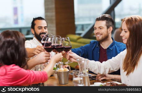 leisure, celebration, food and drinks, people and holidays concept - smiling friends having dinner and drinking red wine at restaurant