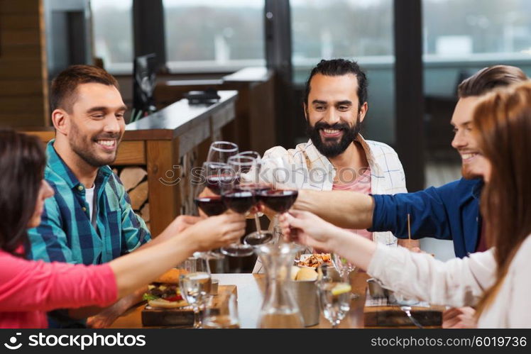 leisure, celebration, food and drinks, people and holidays concept - smiling friends having dinner and drinking red wine at restaurant