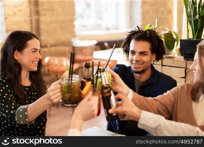 leisure, celebration, party, people and holidays concept - happy friends clinking drinks at bar or cafe. happy friends clinking drinks at bar or cafe