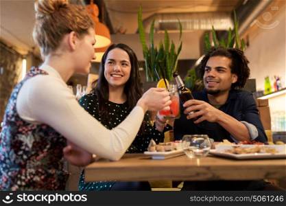leisure, celebration, party, people and holidays concept - happy friends clinking drinks at bar or cafe. happy friends clinking drinks at bar or cafe