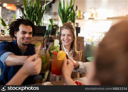 leisure, celebration, party, people and holidays concept - happy friends clinking drinks at restaurant