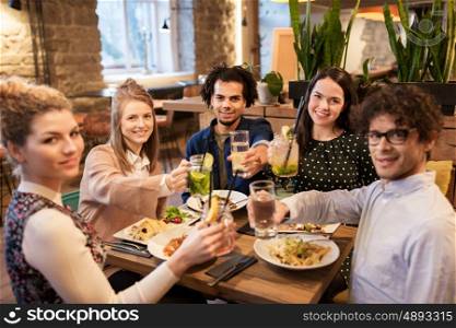 leisure, celebration, party, people and holidays concept - happy friends with drinks and food celebrating at restaurant