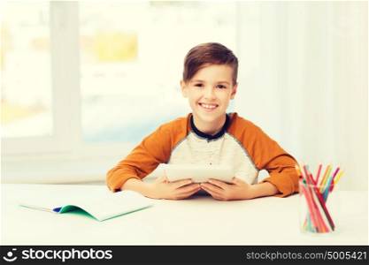 leisure, children, education, technology and people concept - smiling boy with tablet pc computer and notebook at home. smiling boy with tablet pc and notebook at home