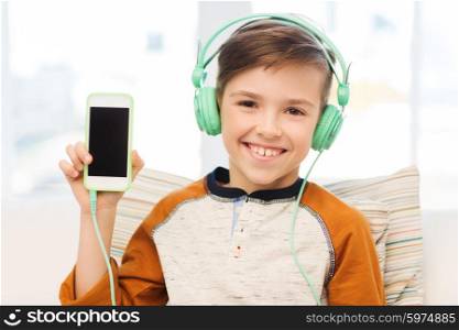 leisure, children, technology, advertisement and people concept - smiling boy with smartphone and headphones listening to music at home