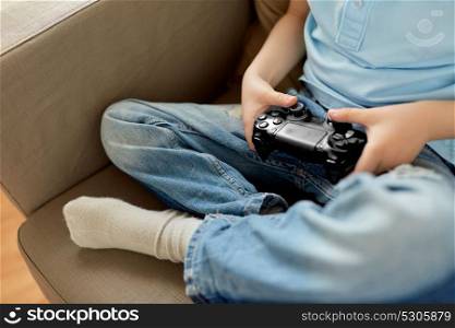 leisure, children, technology and people concept - close up of little boy with gamepad playing video game at home. little boy with gamepad playing video game at home