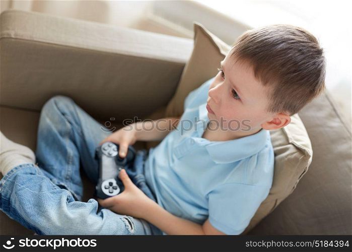 leisure, children, technology and people concept - little boy with gamepad playing video game at home. little boy with gamepad playing video game at home