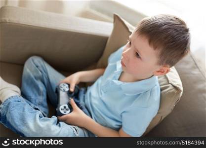 leisure, children, technology and people concept - little boy with gamepad playing video game at home. little boy with gamepad playing video game at home