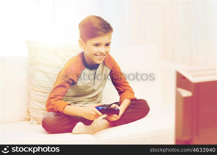leisure, children, technology and people concept - smiling boy with joystick playing video game at home
