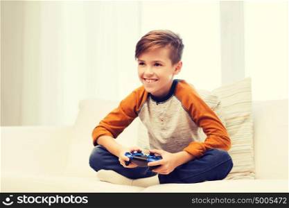leisure, children, technology and people concept - smiling boy with joystick playing video game at home. happy boy with joystick playing video game at home