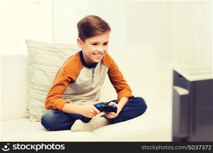 leisure, children, technology and people concept - smiling boy with joystick playing video game at home. happy boy with joystick playing video game at home