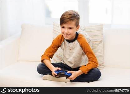 leisure, children, technology and people concept - smiling boy with joystick playing video game at home