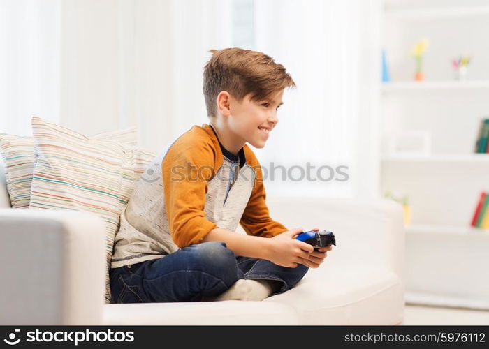 leisure, children, technology and people concept - smiling boy with joystick playing video game at home