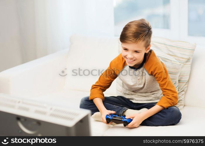 leisure, children, technology and people concept - smiling boy with joystick playing video game at home