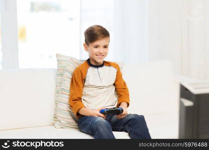 leisure, children, technology and people concept - smiling boy with joystick playing video game at home