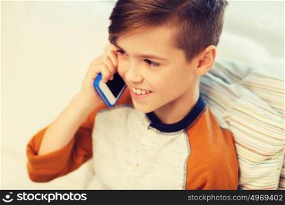 leisure, children, technology, communication and people concept - smiling boy calling on smartphone at home. happy boy calling on smartphone at home