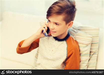 leisure, children, technology, communication and people concept - smiling boy calling on smartphone at home. happy boy calling on smartphone at home