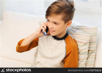 leisure, children, technology, communication and people concept - smiling boy calling on smartphone at home