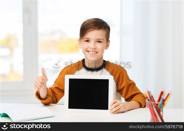leisure, children, technology, education and people concept - smiling boy showing empty tablet pc computer screen and showing thumbs up at home
