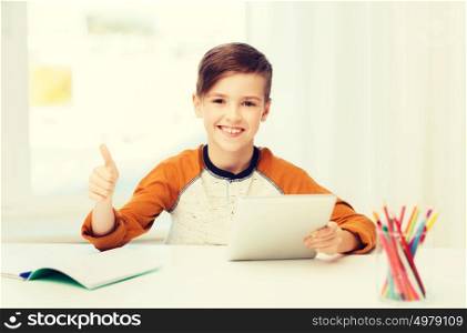 leisure, children, technology, education and people concept - smiling boy with tablet pc computer and notebook showing thumbs up at home. happy boy with tablet pc showing thumbs up at home