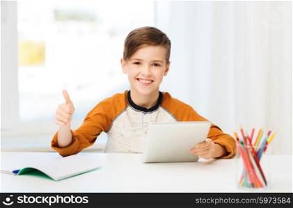 leisure, children, technology, education and people concept - smiling boy with tablet pc computer and notebook showing thumbs up at home