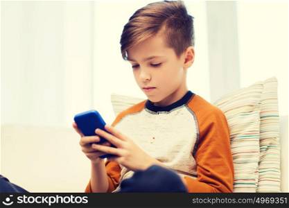 leisure, children, technology, internet addiction and people concept - boy with smartphone texting message or playing game at home. boy with smartphone texting or playing at home
