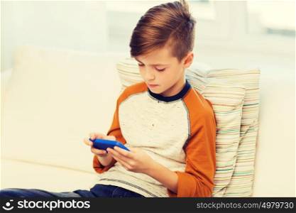 leisure, children, technology, internet addiction and people concept - boy with smartphone texting message or playing game at home. boy with smartphone texting or playing at home