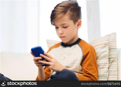 leisure, children, technology, internet addiction and people concept - boy with smartphone texting message or playing game at home