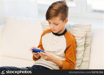 leisure, children, technology, internet addiction and people concept - boy with smartphone texting message or playing game at home